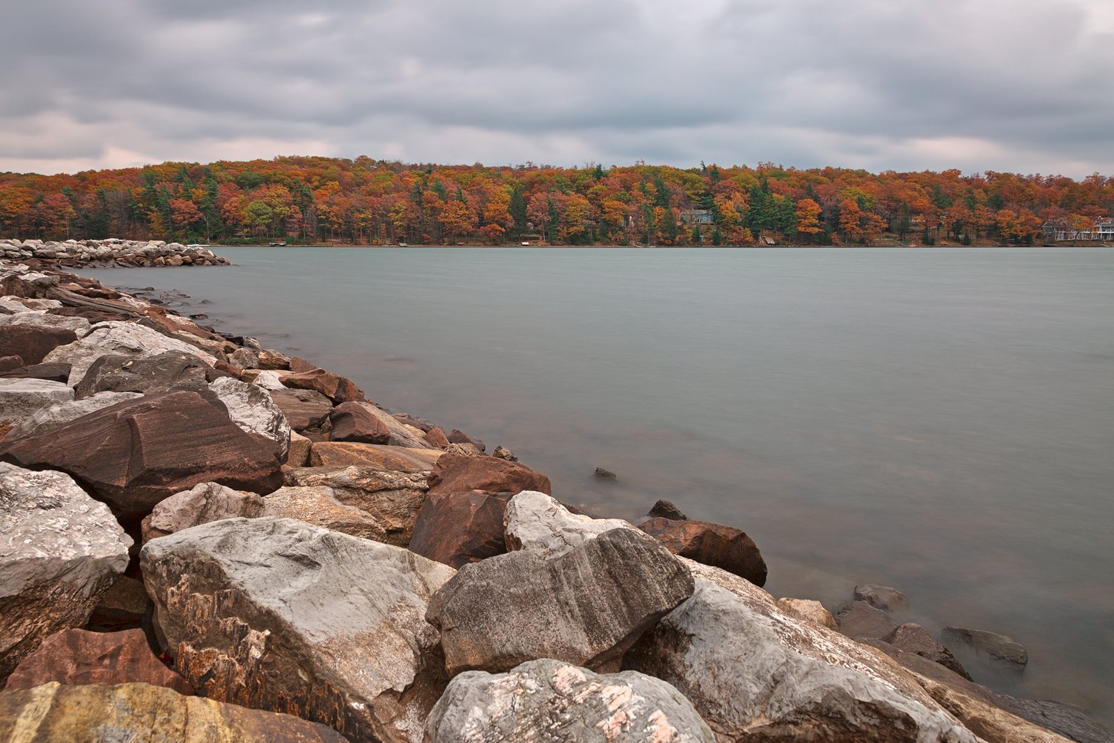 Deep Creek Lake under a gray sky, its far shore a band of orange and rust trees.