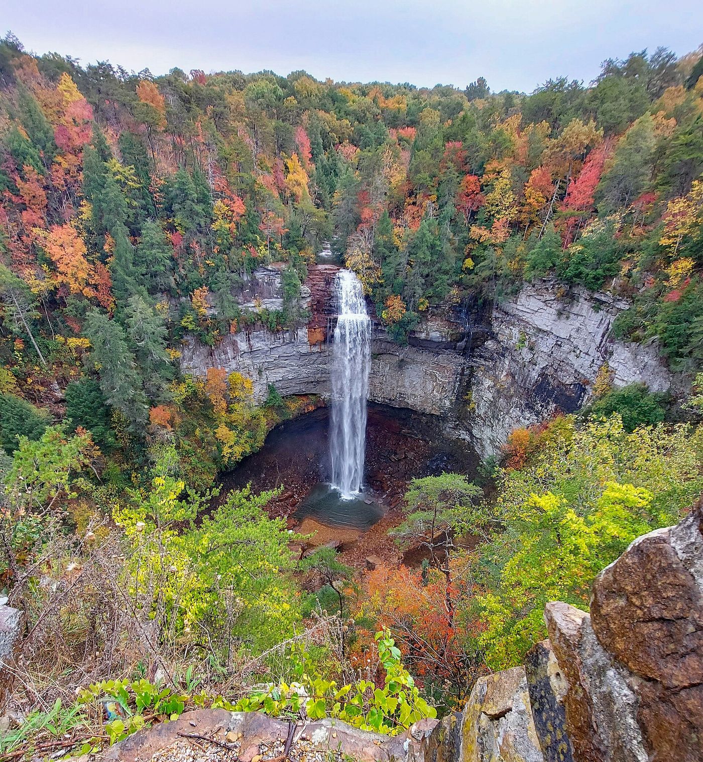 Fall Creek Falls dropping into a gorge ringed by red, orange and yellow trees.